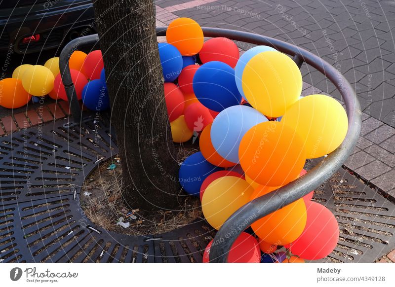 Bunte farbenfrohe Luftballons zu Füßen eines Alleebaum in der Berger Straße vor einem Geschäft im Stadtteil Bornheim in Frankfurt am Main in Hessen Ballon bunt