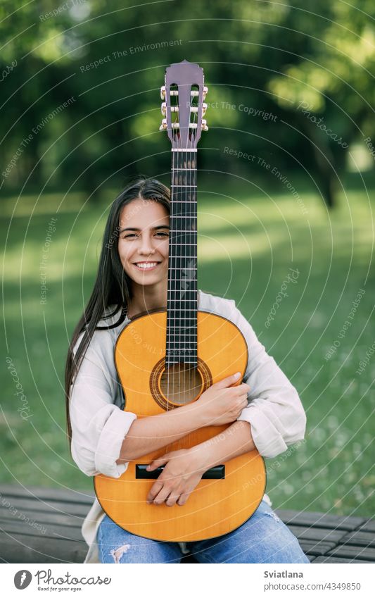 Porträt eines jungen Mädchens Gitarrist, der lächelt und hält eine Gitarre in ihren Händen. Mädchen-Musikerin, Musik, Hobby Park Gitarrenspieler kreativ
