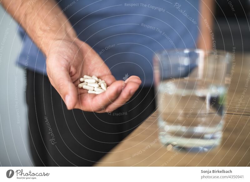 Tabletten bzw. Medikamentenmißbrauch, mann mit Hand voller Kapseln und Wasserglas tabletten medikamente kapseln nahrungsergänzungsmittel medizin sucht