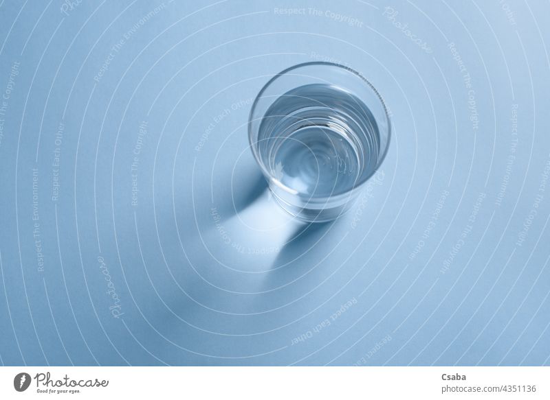 Draufsicht auf ein Glas mit sauberem Trinkwasser auf blauem Hintergrund Wasser Sauberkeit übersichtlich minimalistisch Getränk trinken liquide durchsichtig Top