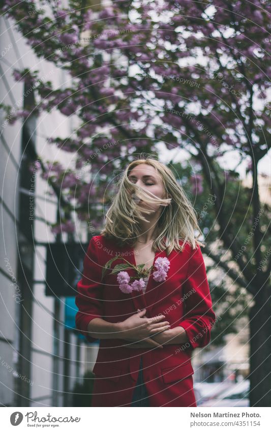 Porträt einer kaukasischen blonden Frau, die eine rote formale Jacke trägt und Blumen hält Model Lifestyle Kaukasier Straße urban selbstbewusst Natur natürlich