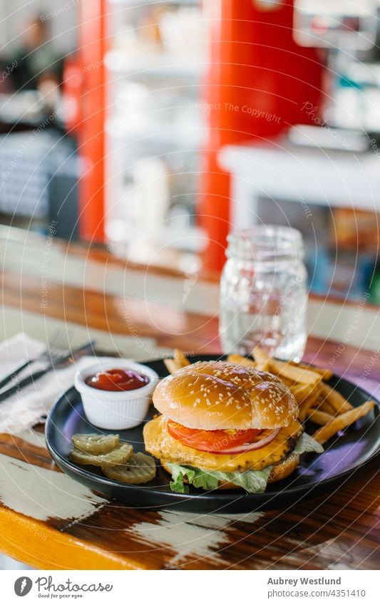 hausgemachter Cheeseburger mit Pommes frites in einem Diner Amerikaner Hintergrund Barbecue grillen Rindfleisch groß Brot Brötchen Burger Cheddar Käse Küche