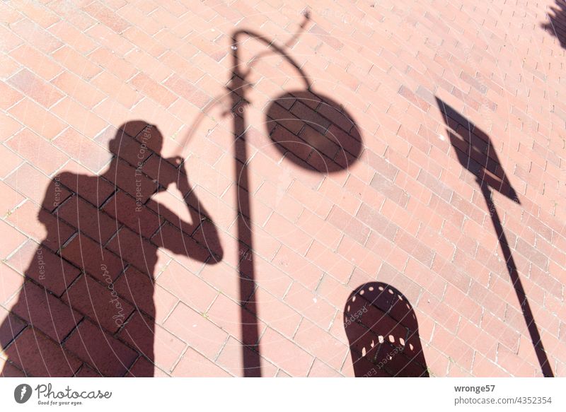 Wo Sonne ist, da ist auch Schatten Sprichwort sprichwörtlich Selfi Fußweg Schattenspiel Fotograf Laterne Straßenlaterne Verkehrsschild Papierkorb