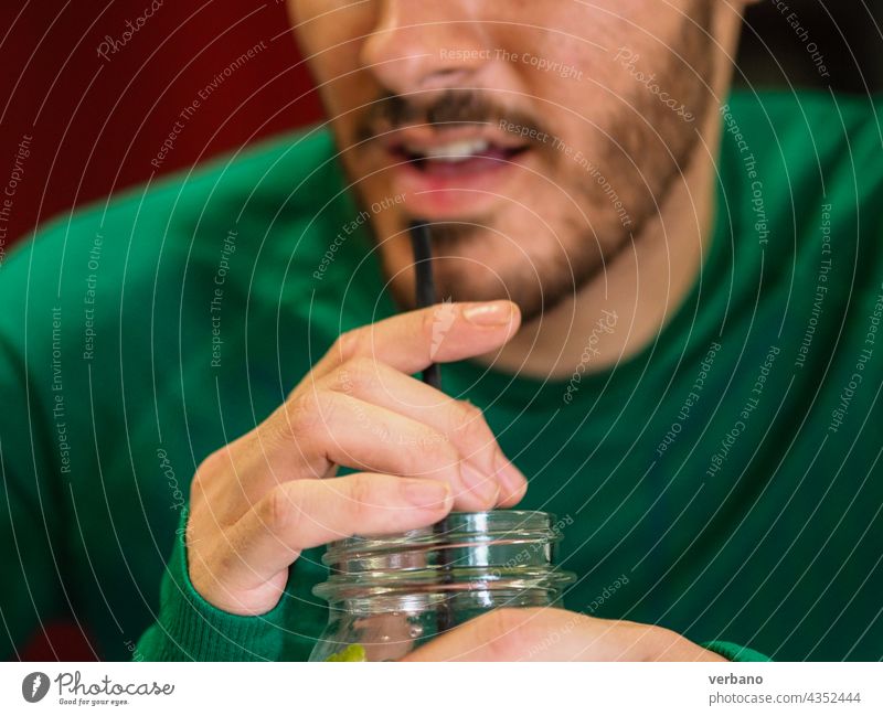 junge Person, die einen Cocktail auf einem Glas mit einem Strohhalm trinkt Mann Kaukasier Mund trinken Saft Getränk Frucht Sommer kalt Eis Hintergrund süß