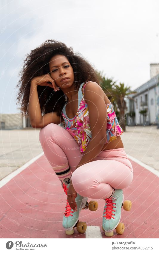 Porträt einer schönen jungen Afro-Frau auf Rollschuhen mit städtischem Hintergrund Afro-Look Skater lockig schwarz Aussehen Behaarung Nahaufnahme Latein Auge
