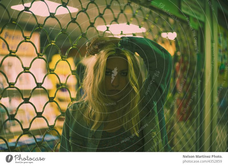 Porträt eines selbstbewussten blonden Modells mit Lichtern und einer Gittertür im Hintergrund Kaukasier Raster ineinander greifen Bokeh Lifestyle Gitternetz