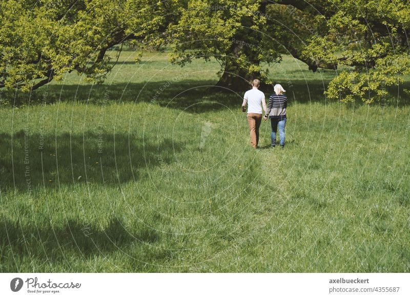 junges Paar hält Händchen bei Spaziergang in der Natur pärchen Händchenhalten Zusammensein Liebe Partnerschaft romantisch Lifestyle Romantik Sommer Park Wiese