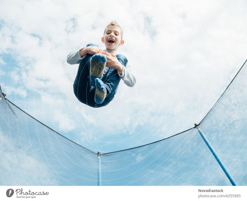 Junge springt auf Trampolin männlich jung Kind allein 1 springen springend hoch im Freien Lächeln genießen Freude Glück Aktion Bewegung Model lässig Gesundheit