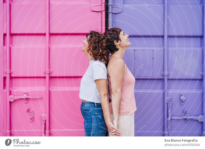 glückliches lesbisches Paar lächelnd und Hände haltend über rosa und lila Hintergrund. Liebe ist Liebe. LGTBI-Konzept Umarmung Zusammensein purpur Frauen
