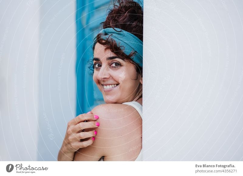 Porträt einer lächelnden kaukasischen Frau, die im Sommer vor einer blauen Tür sitzt. Lebensstil im Freien Glück Kaukasier blaue Tür Großstadt Strand sorgenfrei