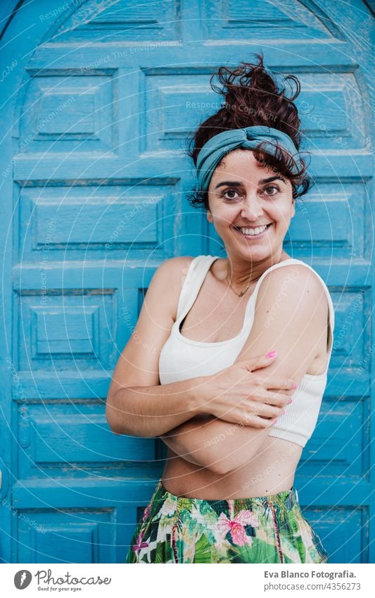 Porträt einer glücklichen kaukasischen Frau, die im Sommer vor einer blauen Tür sitzt. Lebensstil im Freien Glück Kaukasier blaue Tür Großstadt Strand