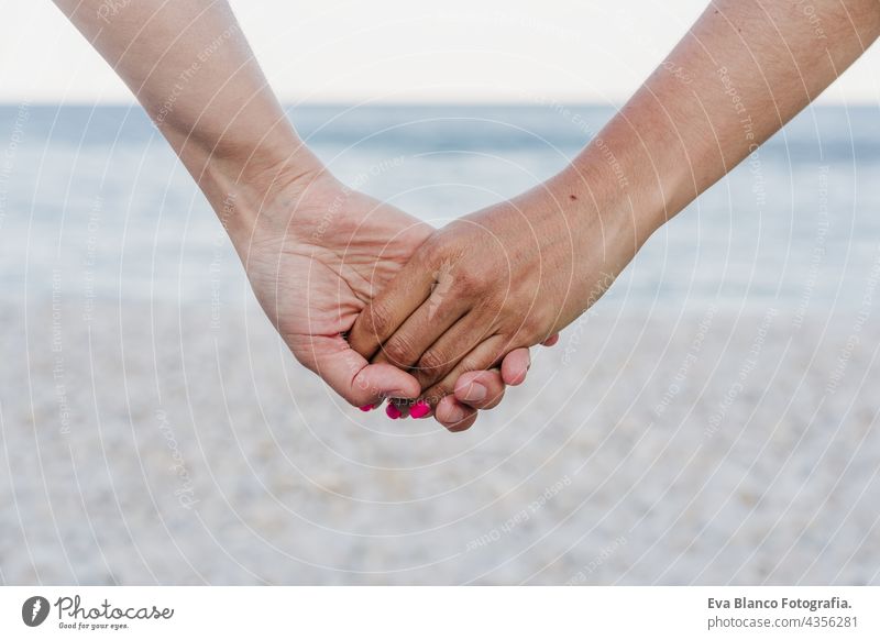 Nahaufnahme eines lesbischen Paares, das sich am Strand bei Sonnenuntergang an den Händen hält. Liebe ist Liebe und LGTBI Konzept unkenntlich abschließen Frauen