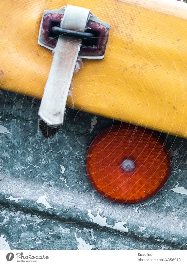 Detail eines Fahrzeugs Nahaufnahme Detailaufnahme Fahrzeugteile Katzenauge Metall orange gelb Anhänger Abdeckung Schnalle
