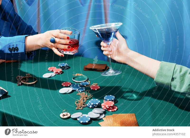 Crop-Frauen stoßen beim Pokerspiel mit Gläsern an Klirren Glas jubelt Schüreisen Spiel Glücksspiel spielen unterhalten Cocktail Freund Wette Postkarte Chip