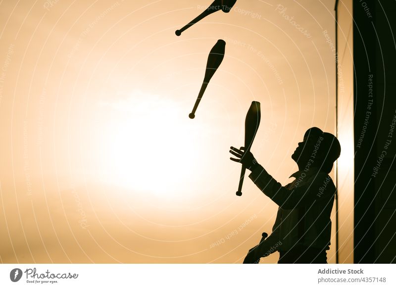 Jongleur mit Keulen gegen Sonnenuntergang Himmel jonglieren Zirkus Trick Künstler ausführen Club unterhalten Mann Talent Kunst Fähigkeit Aktivität üben männlich