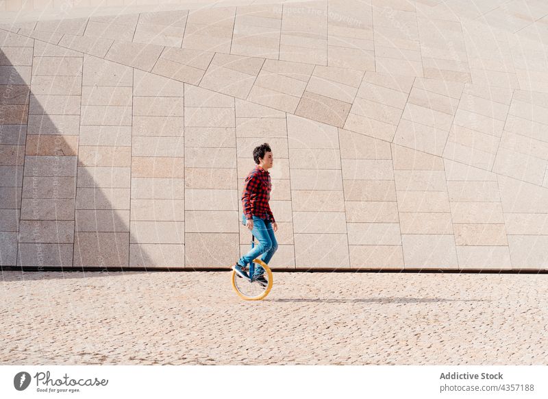 Mann fährt Einrad in der Nähe einer geometrischen Konstruktion Mitfahrgelegenheit modern Architektur Geometrie Gebäude Rad urban Verkehr alternativ männlich