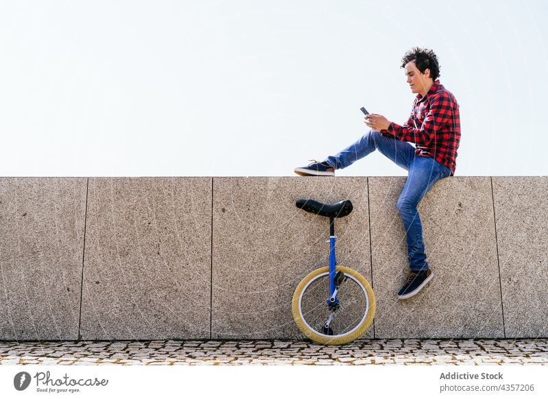 Junger Mann mit Einrad und Smartphone auf der Straße benutzend Telefon urban modern Mobile online Apparatur männlich jung Rad Surfen Kommunizieren Funktelefon