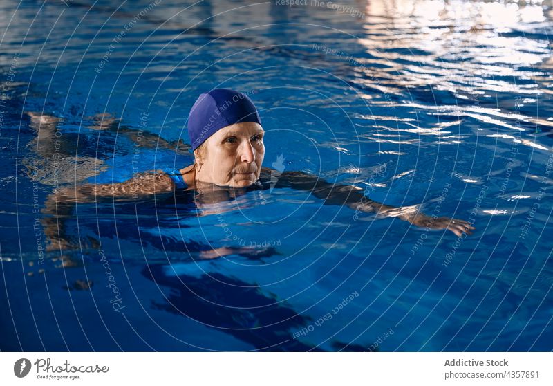 Reife Frau beim Schwimmen im Pool während der Wassergymnastik schwimmen reif Aerobic Übung Training Schwimmer Badeanzug Lebensmitte Fokus Konzentration