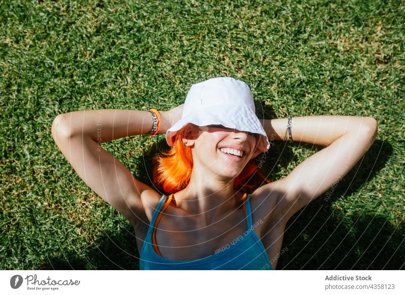 Fröhliche Frau im Gras liegend Lügen Sommer sonnig Glück Park grün schön Rotschopf Hut Natur jung Fröhlichkeit Person sich[Akk] entspannen Frühling Feld Rasen