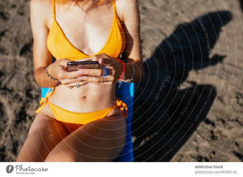 Anonyme Frau mit Telefon am Strand sitzend Bikini benutzend passen Sommer Urlaub MEER reisen Technik & Technologie Browsen Feiertag blass anonym jung Rotschopf