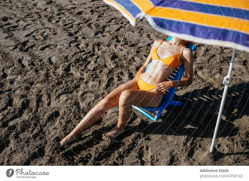 Anonyme Frau am Strand sitzend Bikini passen Sommer Urlaub Sonnenschirm MEER reisen Feiertag blass anonym jung Rotschopf schlank orange Wasser Stuhl Sand