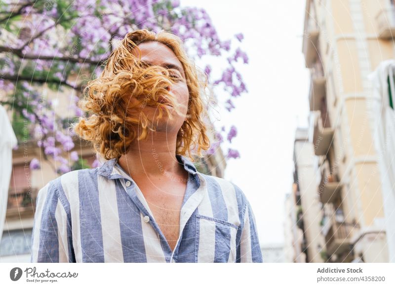 Sorgloser Mann mit langen Haaren in der Stadt fliegendes Haar lange Haare sorgenfrei verträumt Straße Sommer Vorschein Gelassenheit Angebot männlich urban