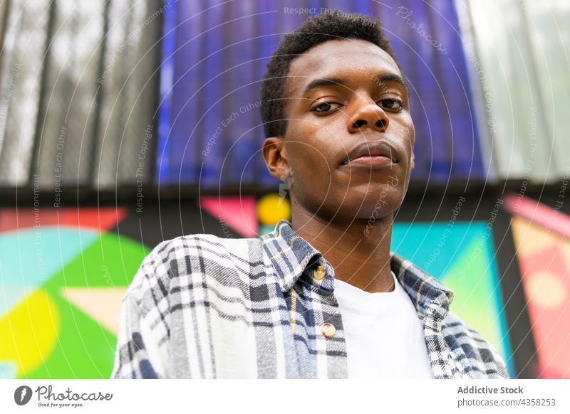 Schwarzer Mann schaut in die Kamera auf buntem Hintergrund sorgenfrei verträumt Straße Großstadt Stil Gelassenheit ruhig genießen männlich ethnisch schwarz