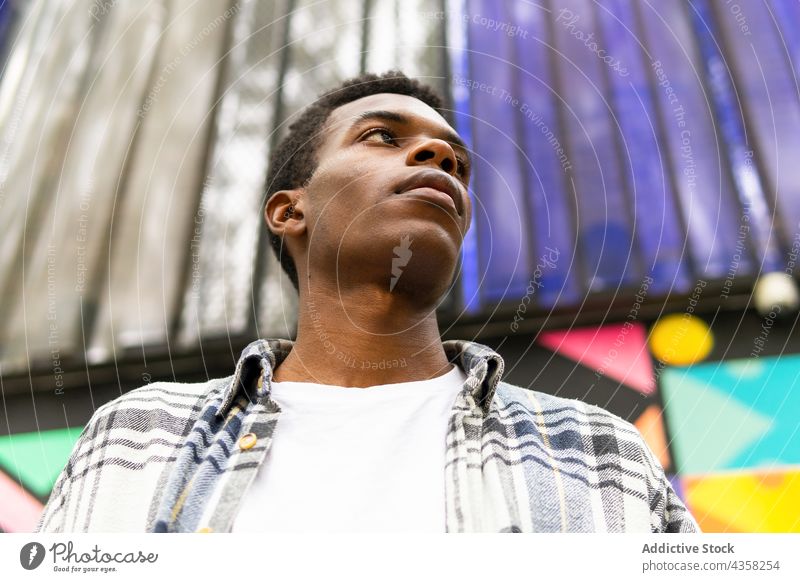 Schwarzer Mann schaut weg auf buntem Hintergrund sorgenfrei verträumt Straße Großstadt Stil Gelassenheit ruhig genießen männlich ethnisch schwarz Afroamerikaner