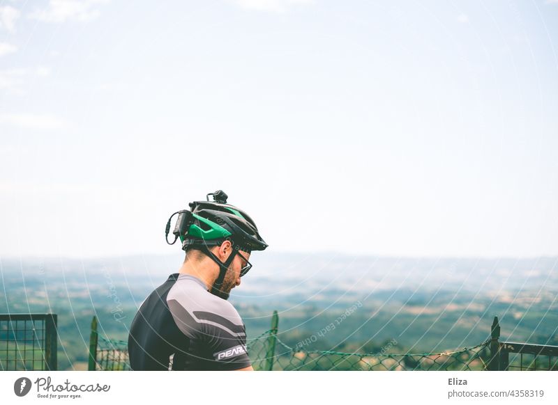 Mann in Fahrradbekleidung mit Fahrradhelm vor einer Aussicht auf die Landschaft Sportkleidung Radsport Fahrradtour Fahrradfahren Freizeit & Hobby sportlich