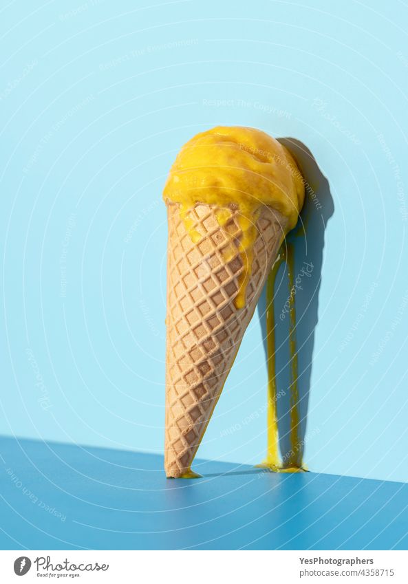 Schmelzende Eiscreme auf blauem Hintergrund. Mango-Eis in einer Waffel. abstrakt hell kalt Farbe Konzept Zapfen Sahne kreativ lecker Dessert Tropf Geschmack