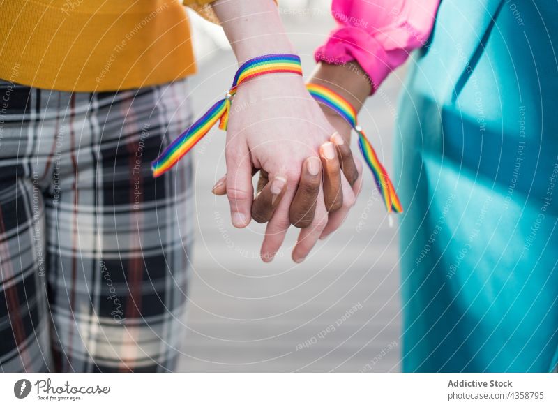 Crop multirassischen lesbischen Paar mit Regenbogen Armbänder halten Hände Frauen lgbt Armband gleich Homosexualität Händchenhalten Stolz multiethnisch