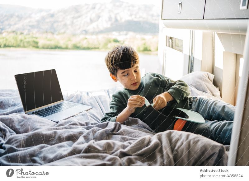 Kleiner Junge entspannt sich in einem Wohnmobil, während er auf dem Bett liegt Schlafzimmer im Innenbereich Erholung Laptop liegend Verschlussdeckel Ferien Kind