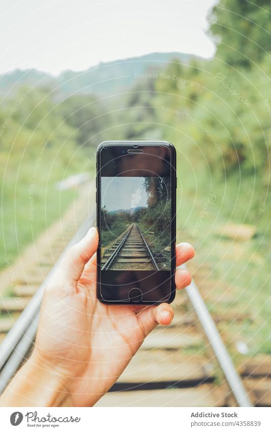 Crop-Reisende, die mit ihrem Smartphone ein Foto von der Eisenbahn machen Reisender fotografieren Natur Schiene Mobile Telefon Apparatur Gerät benutzend