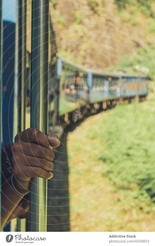 Unkenntlich gemachter ethnischer Mann fährt mit dem Zug und schaut aus dem Waggon reisen Mitfahrgelegenheit Passagier Reisender Fenster Wagen Landschaft