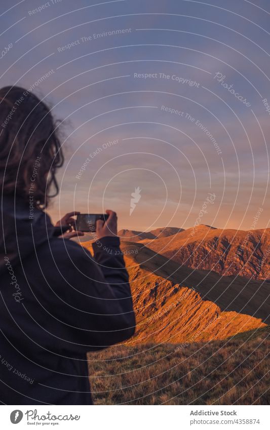 Unbekannter Reisender, der abends mit seinem Smartphone ein Foto von den Bergen macht Mann Wanderer fotografieren Berge u. Gebirge Hochland Ambitus