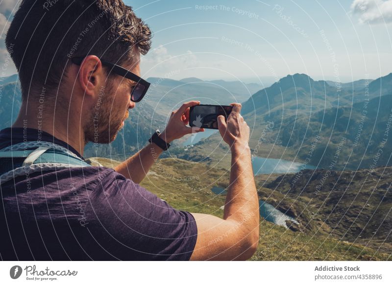 Reisender Mann, der mit seinem Smartphone an einem sonnigen Tag die Berge fotografiert Berge u. Gebirge fotografieren Wanderer reisen Hochland felsig Moment