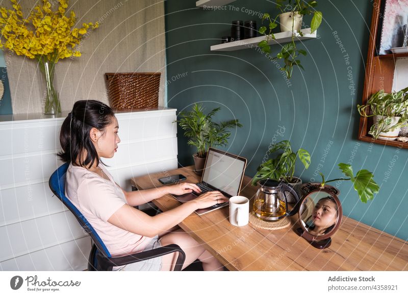 Asiatische Frau liest ein Dokument auf einem Laptop und arbeitet zu Hause freiberuflich Arbeit heimwärts lesen Schriftstück Computer asiatisch ethnisch Netbook