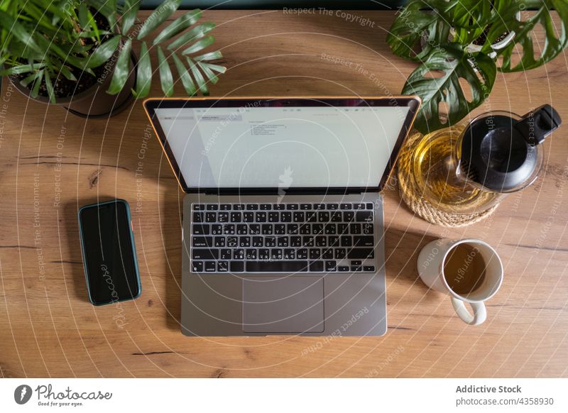 Laptop und Smartphone auf dem Holztisch zu Hause Tisch freiberuflich Arbeitsplatz Tee Apparatur Gerät Netbook Telearbeit Tasse Arbeitsbereich Schreibtisch