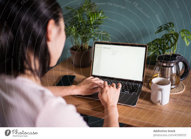 Anonyme asiatische Frau liest ein Dokument auf einem Laptop und arbeitet zu Hause freiberuflich Arbeit heimwärts lesen Schriftstück Computer ethnisch Netbook