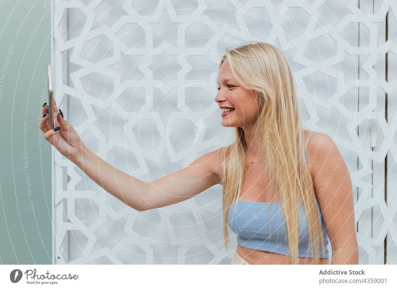 Lächelnde Frau, die ein Selfie mit ihrem Smartphone macht Selbstportrait charmant blond Großstadt urban Moment Gedächtnis attraktiv schön Straße jung heiter