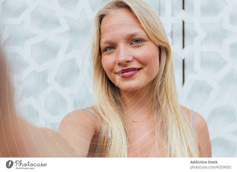 Lächelnde Frau, die ein Selfie mit ihrem Smartphone macht Selbstportrait charmant blond Großstadt urban Moment Gedächtnis Straße attraktiv jung heiter Mobile