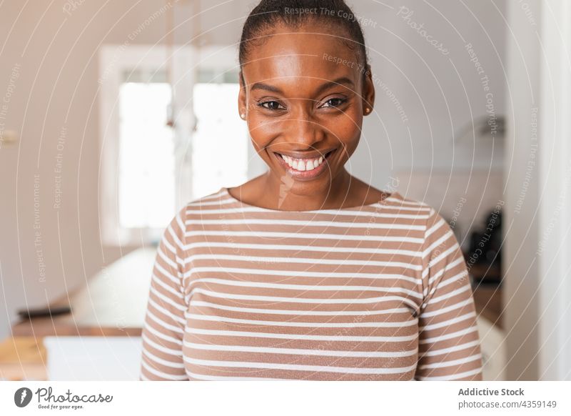 Schwarze Frau in Kleidung mit gestreiftem Ornament zu Hause selbstbewusst Starrer Blick Streifen Fenster Vorrichtung Küche Porträt heimwärts Tisch starren