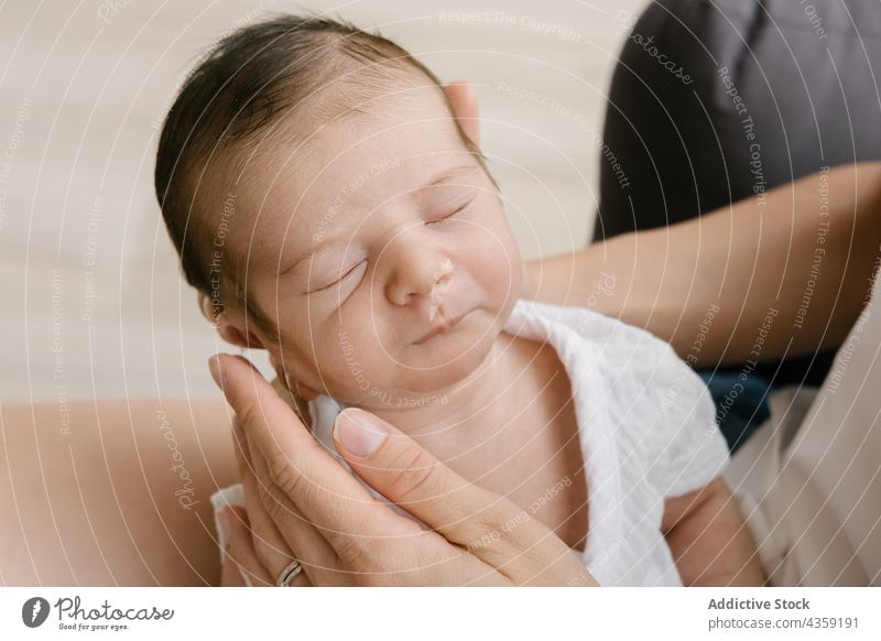 Anonyme zarte Mutter, die mit ihrem Neugeborenen zu Hause auf dem Boden sitzt neugeboren schlafen Baby Zusammensein Liebe filigran Säugling unschuldig heimwärts