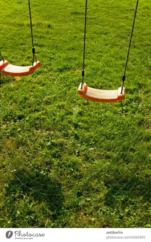 Kinderspielplatz mit Schaukel kinderspielplatz gras rasen wiese schaukel sitz schaukelsitz sitzschale kettenschaukel licht schatten sommer sonne menschenleer