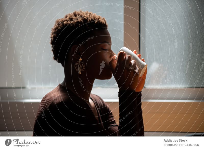 Schwarze Frau trinkt Kaffee aus einer Tasse zu Hause trinken Morgen heimwärts Erfrischung Getränk genießen geschmackvoll sonnig ethnisch schwarz Afroamerikaner