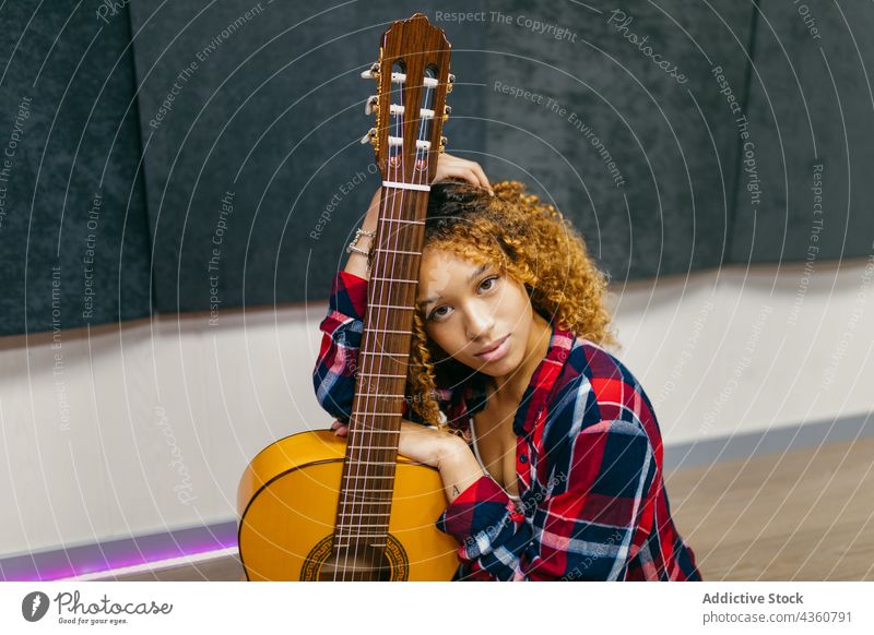 Ein afroamerikanischer Musiker mit einer Gitarre, die in einem Haus auf dem Boden liegt Gitarrenspieler Kunst klassisch akustisch tausendjährig Stock Frau