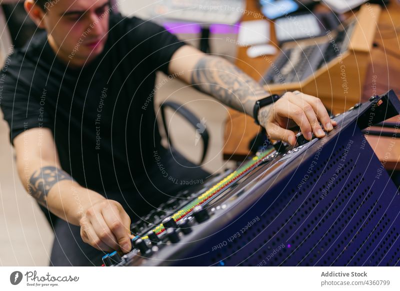 Tonmann bei der Arbeit mit dem Mischpult im Musikstudio Ingenieur Klang Konsole Panel ausrichten Audio Tattoo Mann Atelier benutzend Gerät Kontrolle Knauf