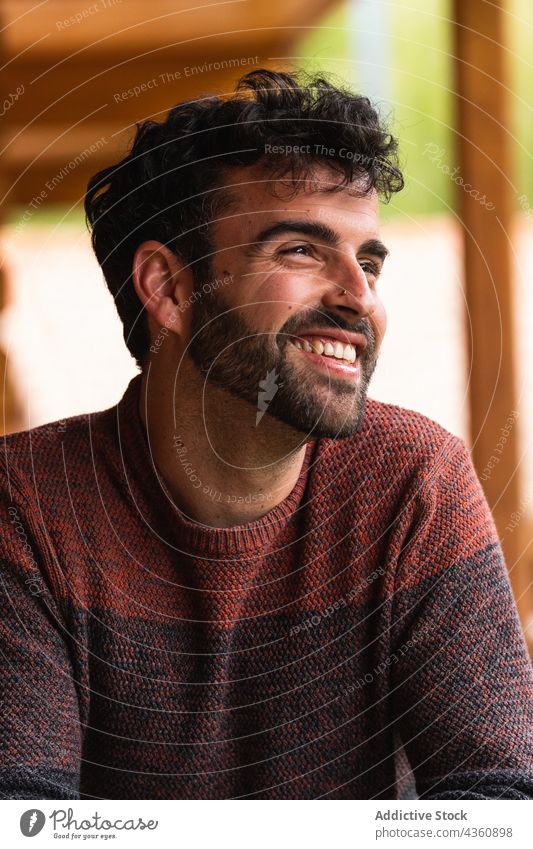 Fröhlicher Mann, der auf der Terrasse chillt und wegschaut Kälte heiter gutaussehend Vorschein Wochenende Urlaub sich[Akk] entspannen Lächeln männlich Pyrenäen