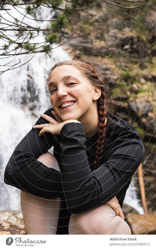 Entzückte Reisende, die vor einem Wasserfall in die Kamera schaut Frau Reisender Wanderer Lächeln Wald Berge u. Gebirge Abenteuer Glück reisen Pyrenäen Wälder