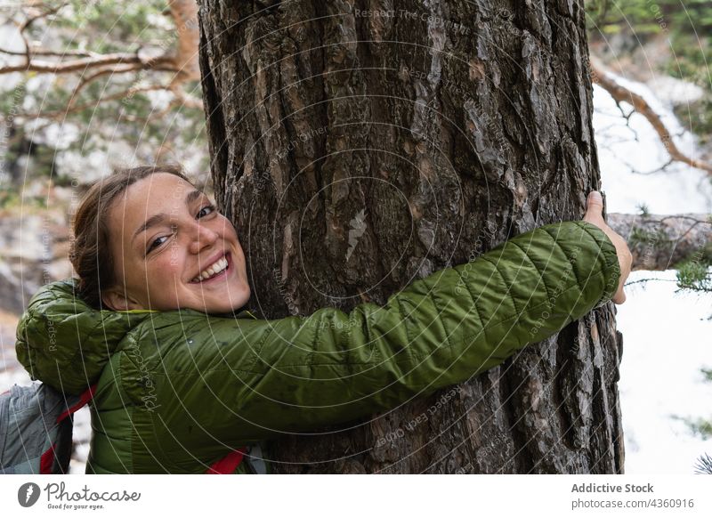Lächelnde reisende Frau, die einen Baum im Wald umarmt Umarmung Reisender Umarmen Kofferraum Wälder genießen Pyrenäen heiter Glück Natur Feiertag positiv